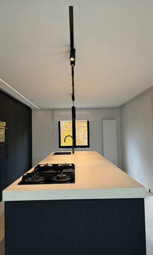 Afgewerkte leefruimte met groot glasfront en strak wit plafond.