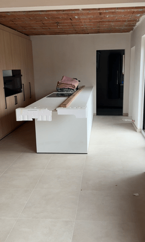 Ruwbouwfase: betonplafond, kabels en bescherming op de vloer.